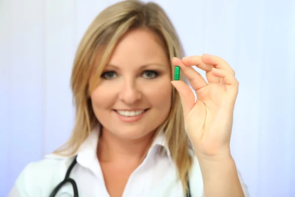 Young beautiful doctor with stethoscope holding multicolor pill, isolated on white — Stock Photo, Image