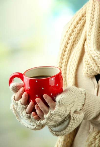 Vrouwelijke handen met warme dranken, op lichte achtergrond — Stockfoto