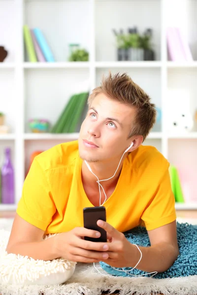 Young man relaxing carpet and listening to music — Stock Photo, Image