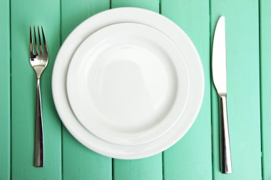 Plate and cutlery on wooden table close-up