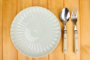 Plate and cutlery on wooden table close-up