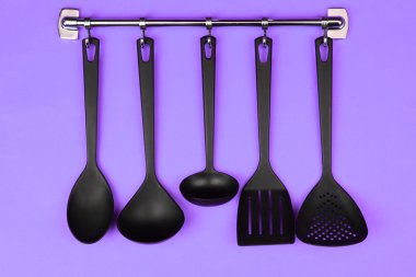 Gümüş kanca, mor arka plan üzerinde siyah mutfak gereçleri