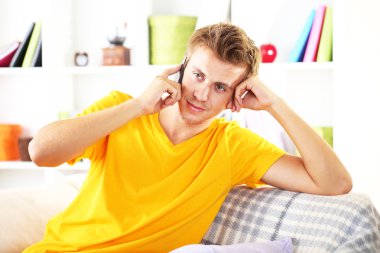 Genç adam cep telefonu ile kanepede rahatlatıcı