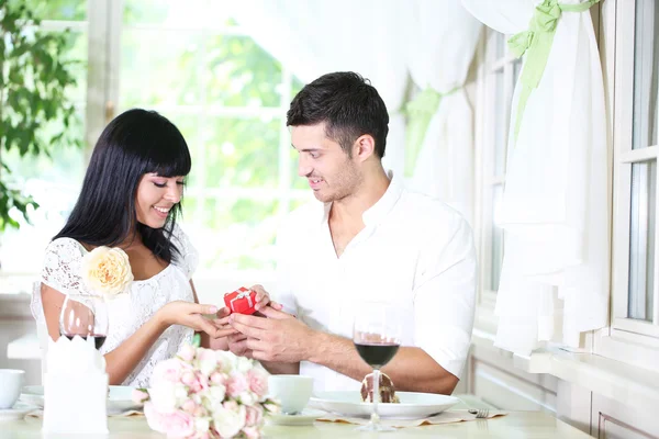 Man proposing and holding up an engagement ring his woman over restaurant table — Stock Photo, Image