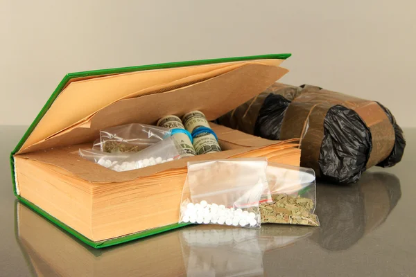 Narkotik kitap saklandığı yerde ve gri arka plan üzerinde paketleri — Stok fotoğraf