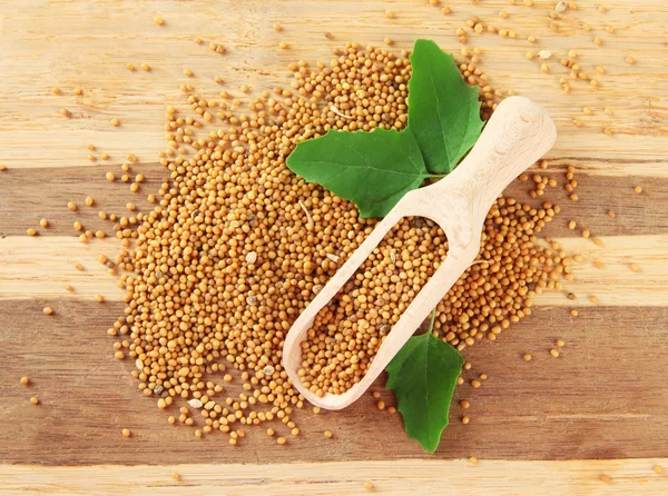 Mustard seeds with mustard leaves on wooden background — Stock Photo, Image