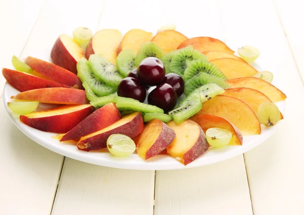 Beyaz ahşap masa üzerinde plaka üzerinde dilimlenmiş meyve çeşitleri — Stok fotoğraf
