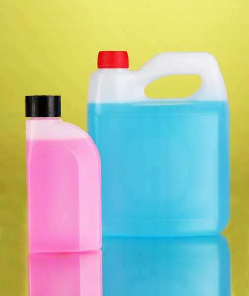 Blue and pink liquids for car in canisters on green background — Stock Photo, Image