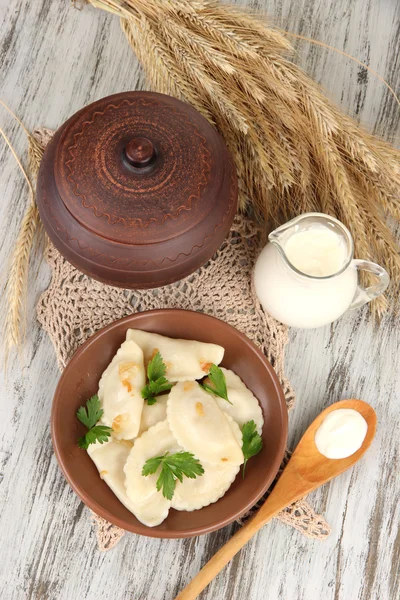 Tasty dumplings with fried onion on brown plate, on wooden background — Stock Photo, Image