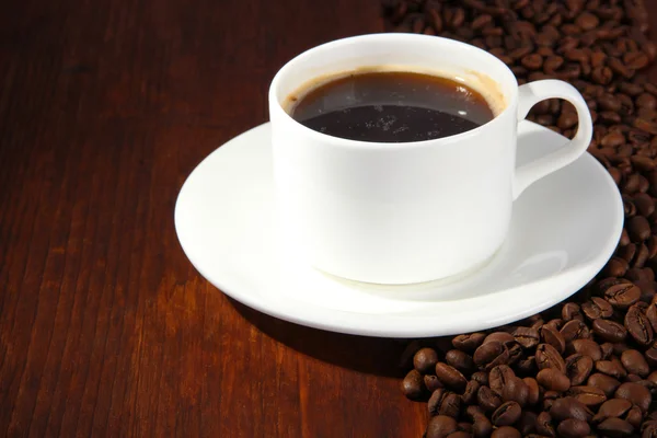 Tazza di caffè con chicchi di caffè su sfondo di legno — Foto Stock