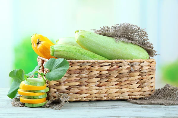 In Scheiben geschnittene und ganze rohe Zucchini in Weidenkiste, im Freien — Stockfoto