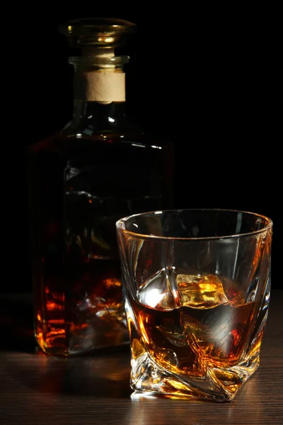 Glass of whiskey with bottle, on dark background — Stock Photo, Image