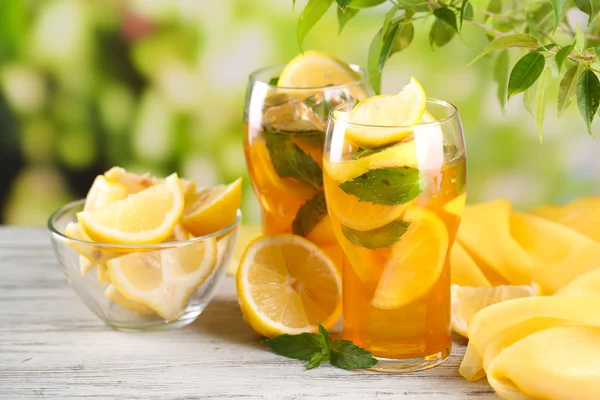 Té helado con limón y menta en la mesa de madera, al aire libre —  Fotos de Stock