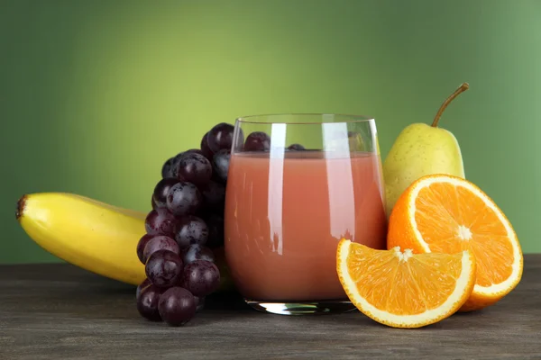 Glass of fresh juice on table on green background — Stock Photo, Image