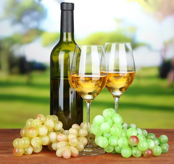 Uvas maduras, garrafa e copos de vinho, sobre fundo brilhante — Fotografia de Stock