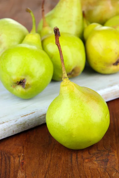 Pears on cutting board, on wooden background — Stock Photo, Image