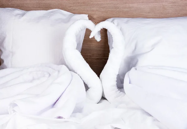 Zwanen gemaakt van handdoeken op bed op houten achtergrond — Stockfoto