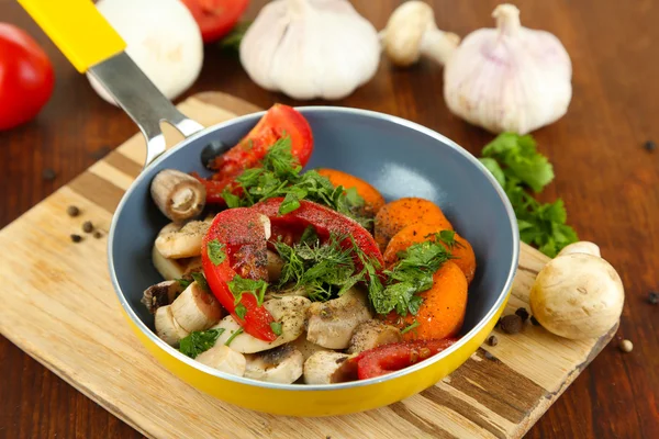 Skivade färska grönsaker i pannan på träbord närbild — Stockfoto