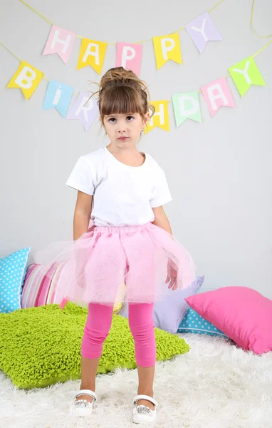 Маленька дівчинка танцює на ліжку в кімнаті на сірому фоні стіни — стокове фото