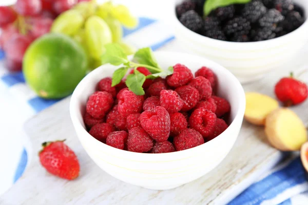 Himbeeren und Brombeeren in kleinen Schalen an Bord auf Serviette isoliert auf weiß — Stockfoto