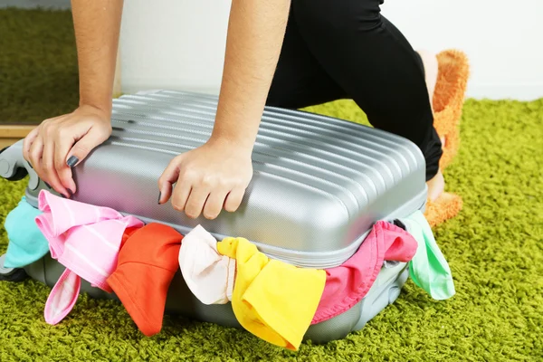 Kuffert med tøj på tæppe på værelse baggrund - Stock-foto