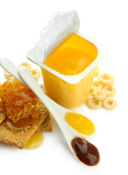 Вкусный десерт в открытой пластиковой чашке и мед расчески, изолированные на белом — стоковое фото