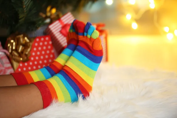 Beine in Socken neben Weihnachtsbaum auf Teppich — Stockfoto