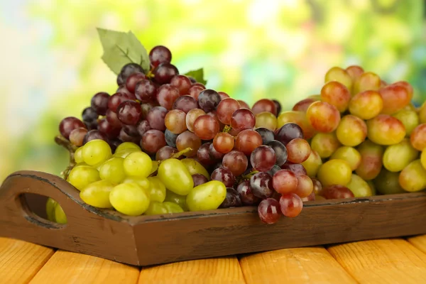 Fresh grape on wooden tray on bright background — Stock Photo, Image