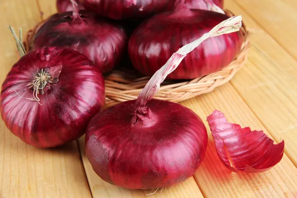 Frische rote Zwiebeln auf Holztisch — Stockfoto