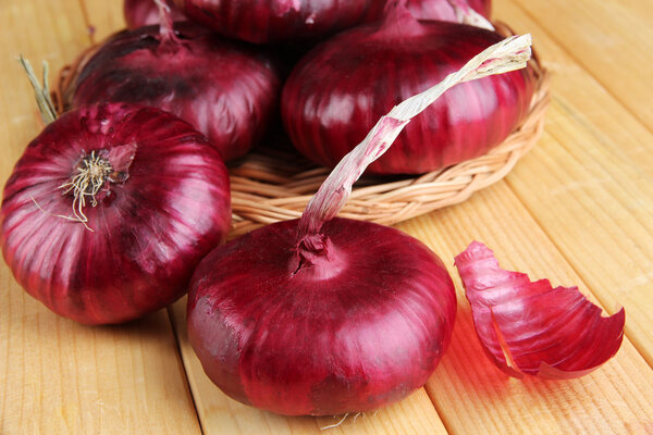 Fresh red onions on wooden table