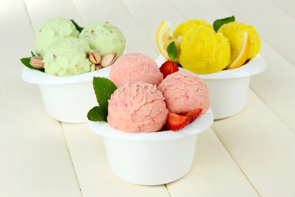 Chutné zmrzlinové kopečky v miskách, na dřevěný stůl — Stock fotografie