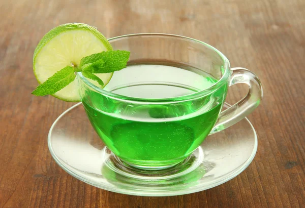 Tazza trasparente di tè verde con lime e menta su sfondo di legno — Foto Stock