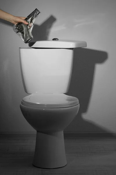 Hand hides gun in toilet tank in a bathroom — Stock Photo, Image