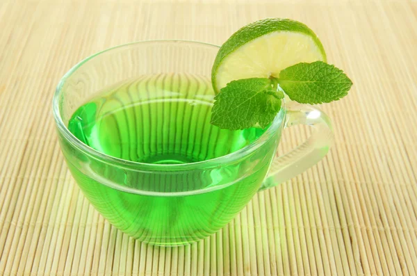 Taza transparente de té verde con lima y menta sobre fondo de bambú —  Fotos de Stock