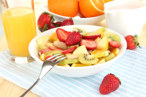 Useful fruit salad of fresh fruits and berries in bowl on napkin on wooden table close-up — Stock Photo, Image