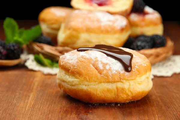 Leckere Donuts mit Schokolade auf Holztisch — Stockfoto