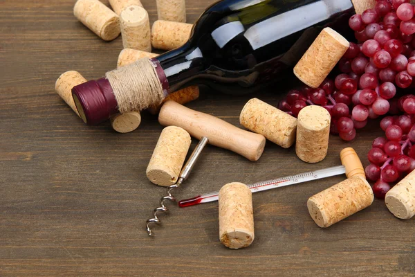 Bottle of wine, grapes and corks on wooden background — Stock Photo, Image