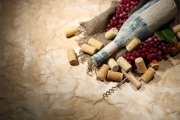 Vecchia bottiglia di vino, uva e tappi su vecchio sfondo di carta — Foto Stock