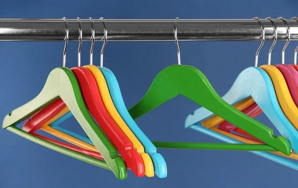 Colorful clothes hangers on blue background — Stock Photo, Image