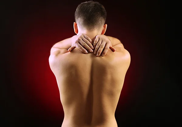Jovem com dor no pescoço, em fundo vermelho — Fotografia de Stock