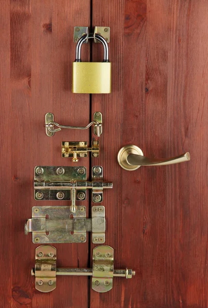 Kovové šrouby, zámky a zavěsí v dřevěné dveře detail — Stock fotografie