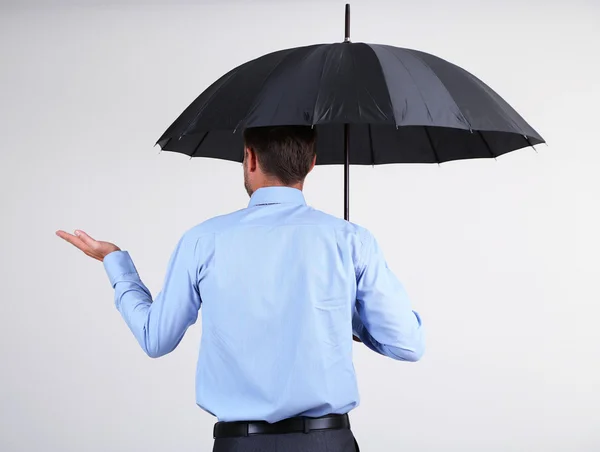 Geschäftsmann mit Regenschirm. auf grauem Hintergrund — Stockfoto