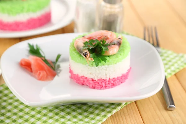 Colored rice on plates on napkin on wooden table — Stock Photo, Image