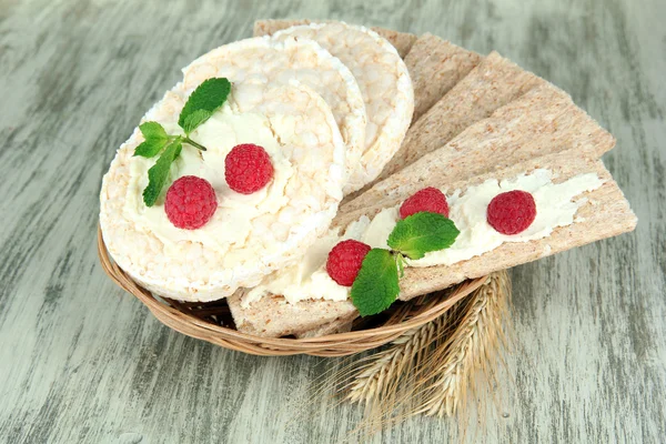 Smakelijke knäckebröd met bessen in rieten mand, op houten tafel — Stockfoto