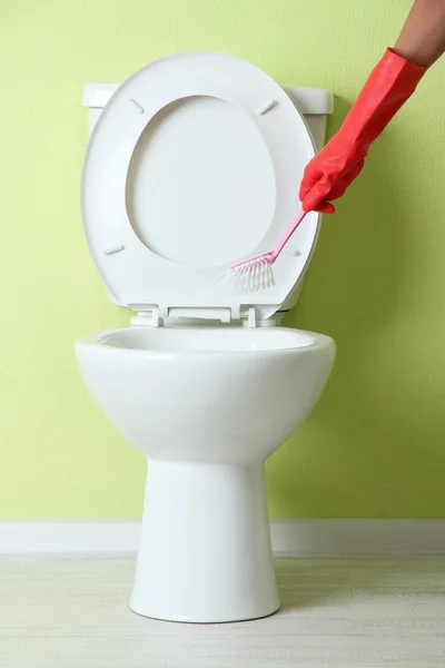 Woman hand with brush cleaning a toilet bowl in a bathroom — Stock Photo, Image