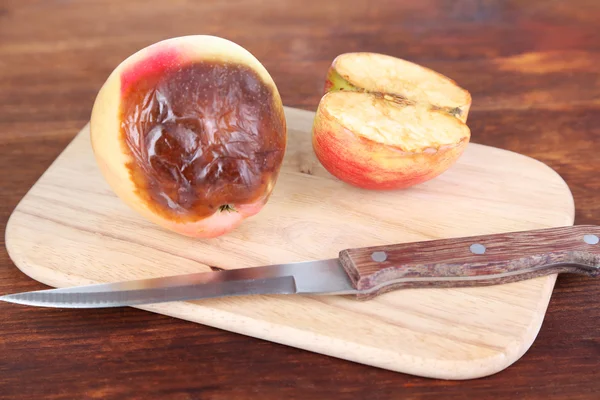 Rotten apples on wooden board on table — Stock Photo, Image