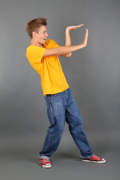 Przystojny młody mężczyzna tańczy na szarym tle — Zdjęcie stockowe