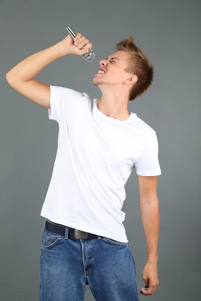 Guapo joven canta sobre fondo gris — Foto de Stock