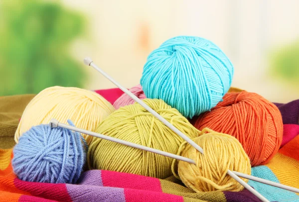 Multicolored clews with needles and bright scarf closeup — Stock Photo, Image
