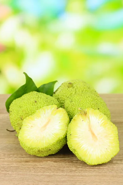 ผลส้มโอเซจ (Maclura pomifera) บนโต๊ะไม้ บนพื้นหลังธรรมชาติ — ภาพถ่ายสต็อก